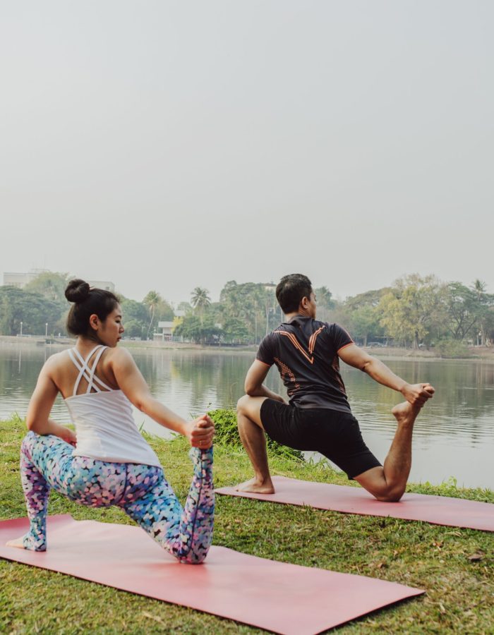 couple-practisisng-yoga-beside-lake